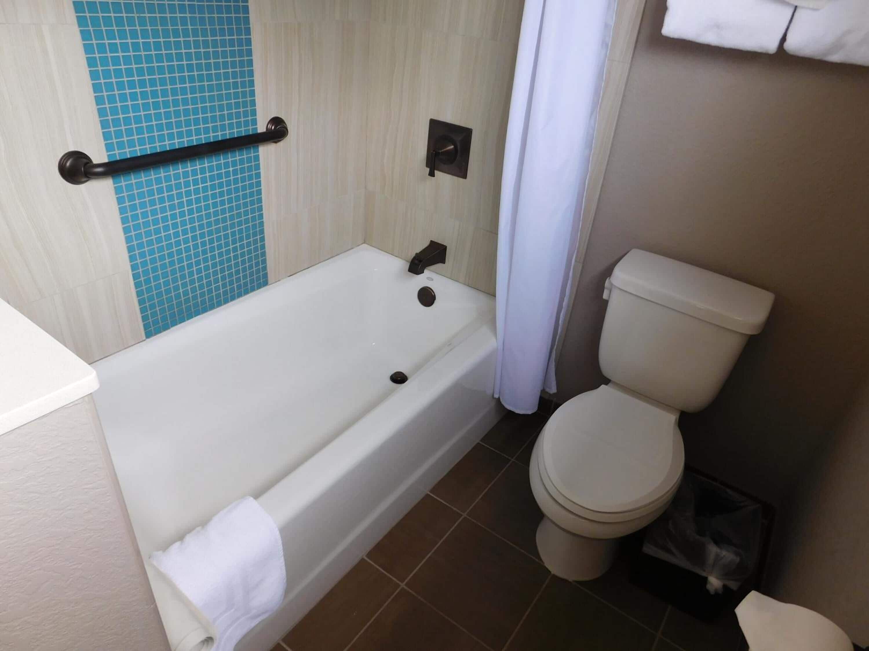 A bathroom with a bathtub, toilet, and a towel rack.