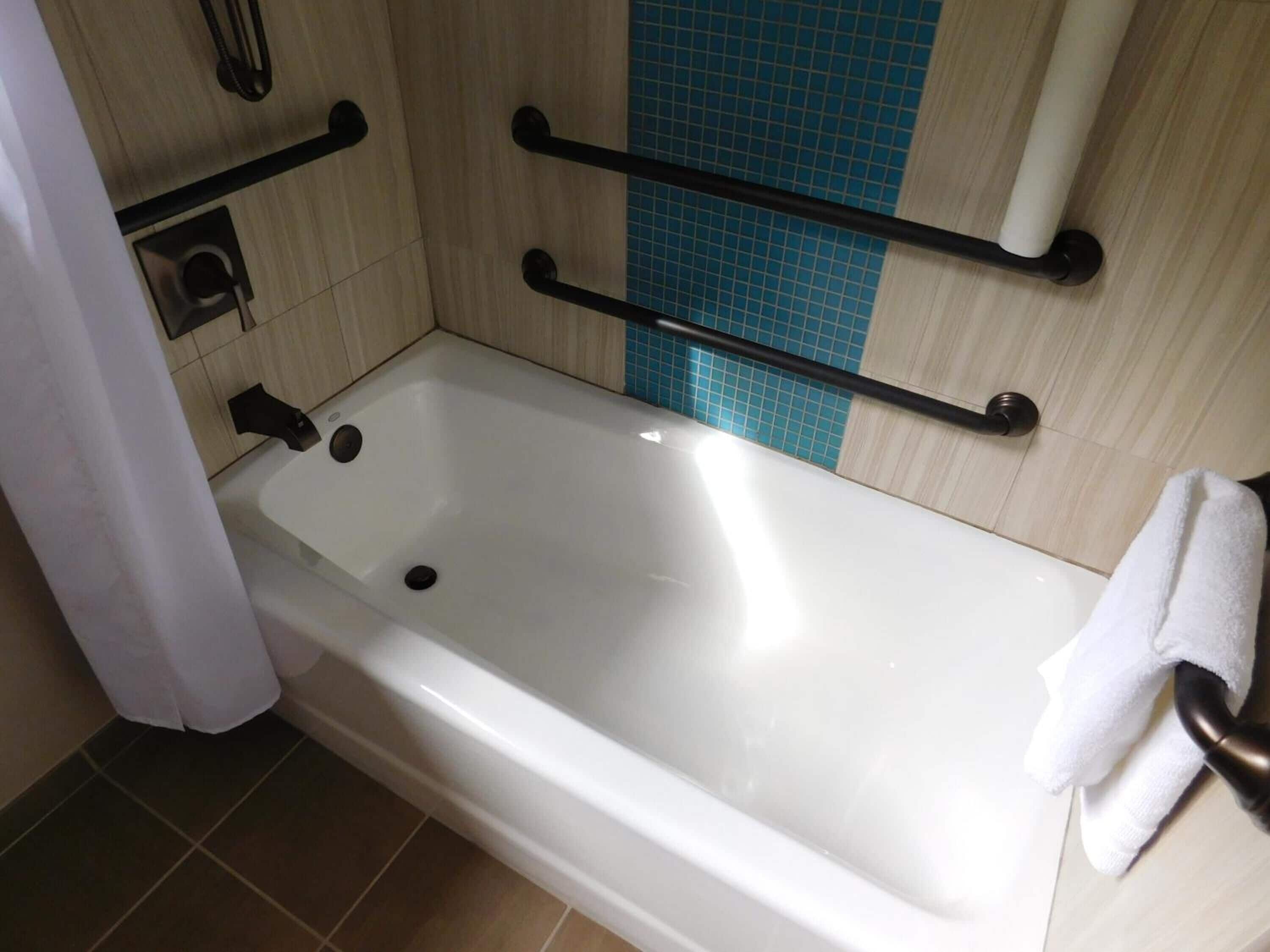 Une salle de bain avec une baignoire blanche, un porte-serviettes et un sèche-mains.