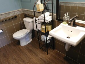 A bathroom with a toilet, a white sink, and a shelf with toiletries.
