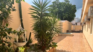 A tiled courtyard with potted plants, a hanging planter, and a small pool. - Hotel Handall Cancun (Cancun)