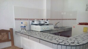 A kitchen with a gas stove, a sink, and a countertop with a patterned backsplash. - Hotel Sarabi Barra de Navidad (Barra de Navidad)