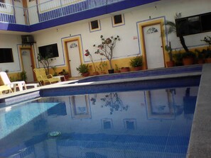 Une piscine offrant une vue dégagée sur l’espace qui l’entoure, notamment sur les chaises longues et les plantes en pot.