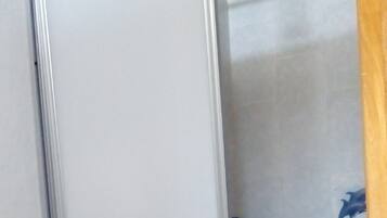 Un baño con ducha, suelo de baldosas y una puerta.