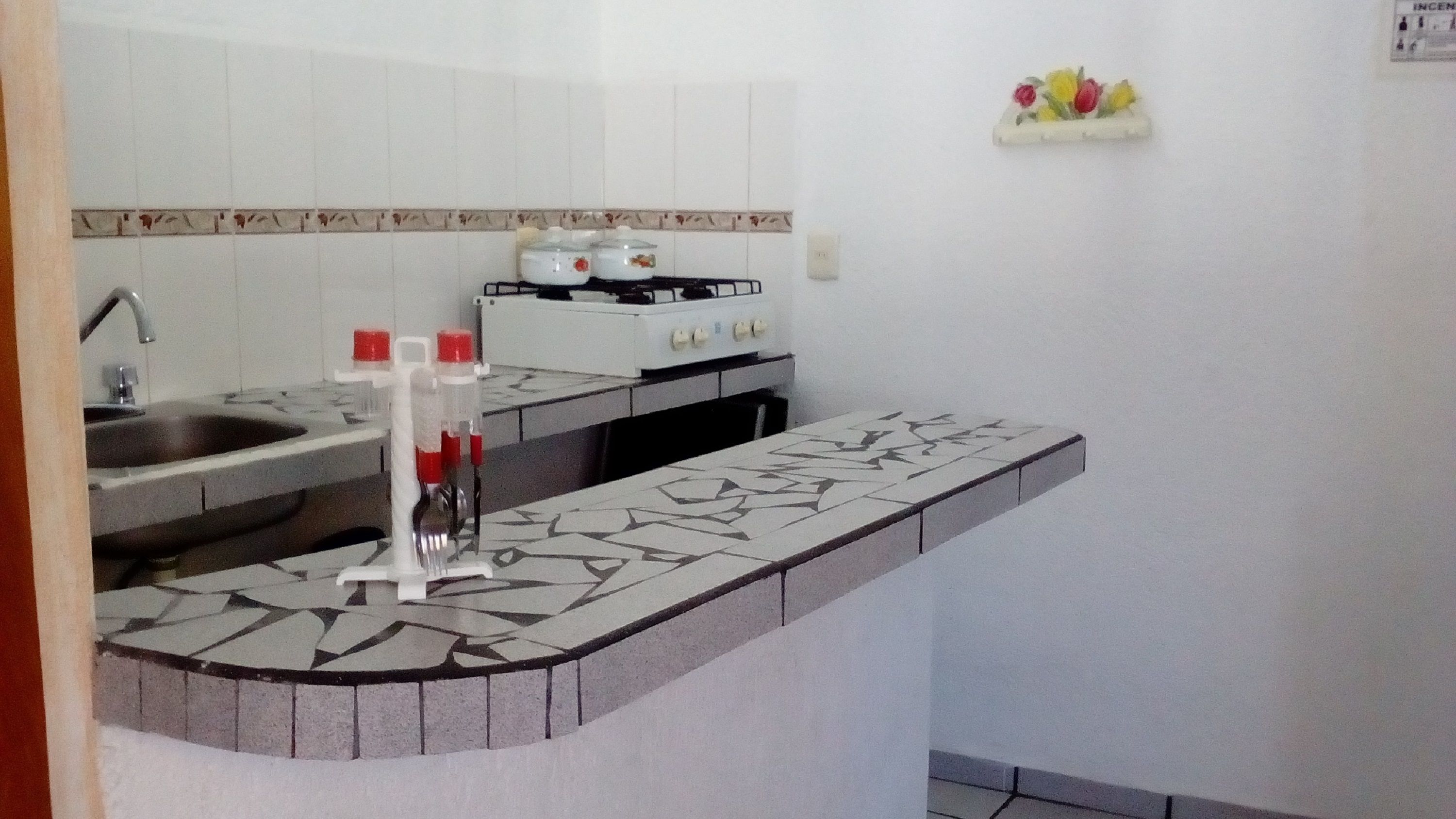 Una cocina pequeña con un lavamanos, una estufa y una pequeña encimera.