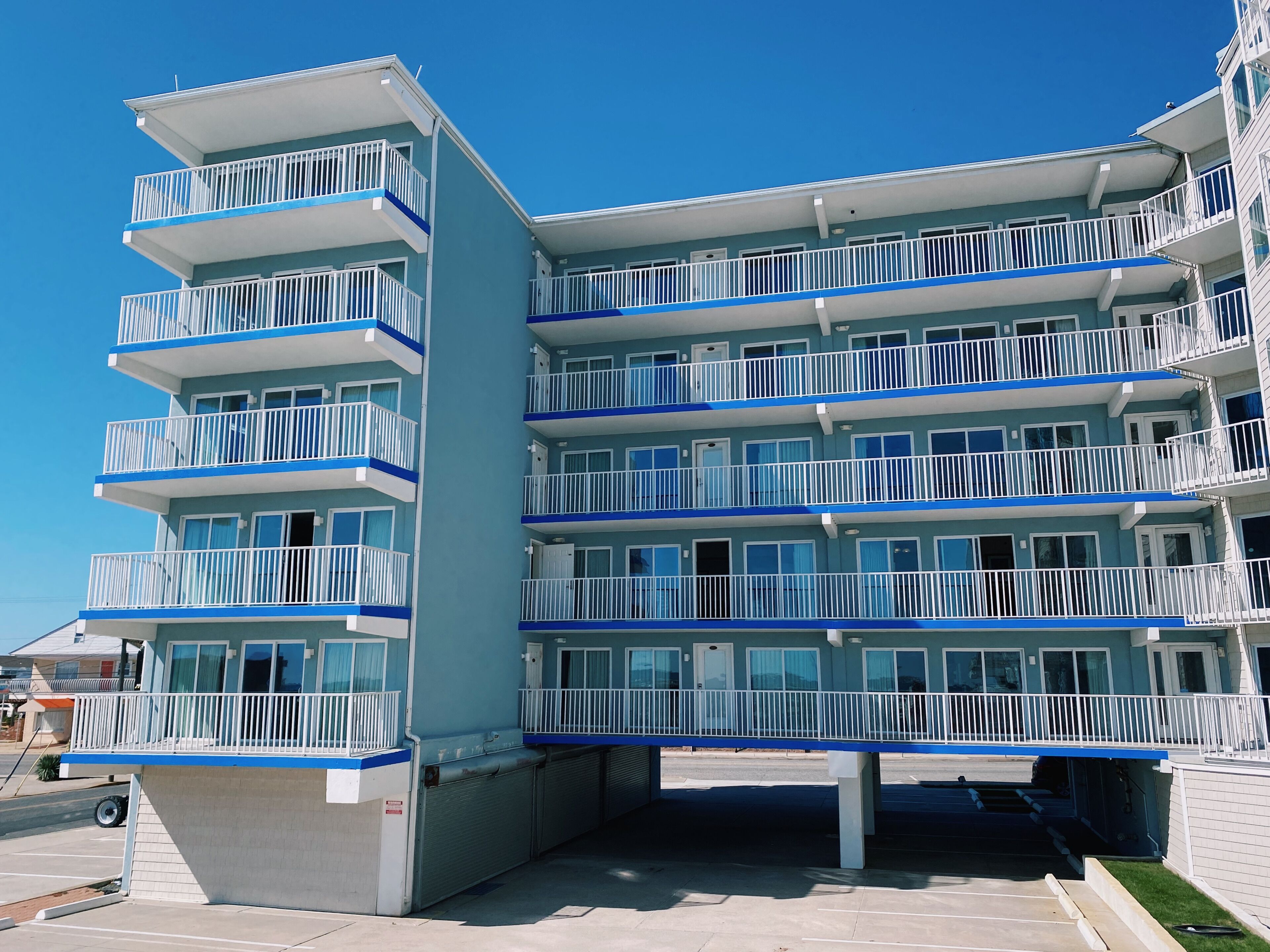 A multi-story hotel with balconies, a covered entrance, and a parking area.
