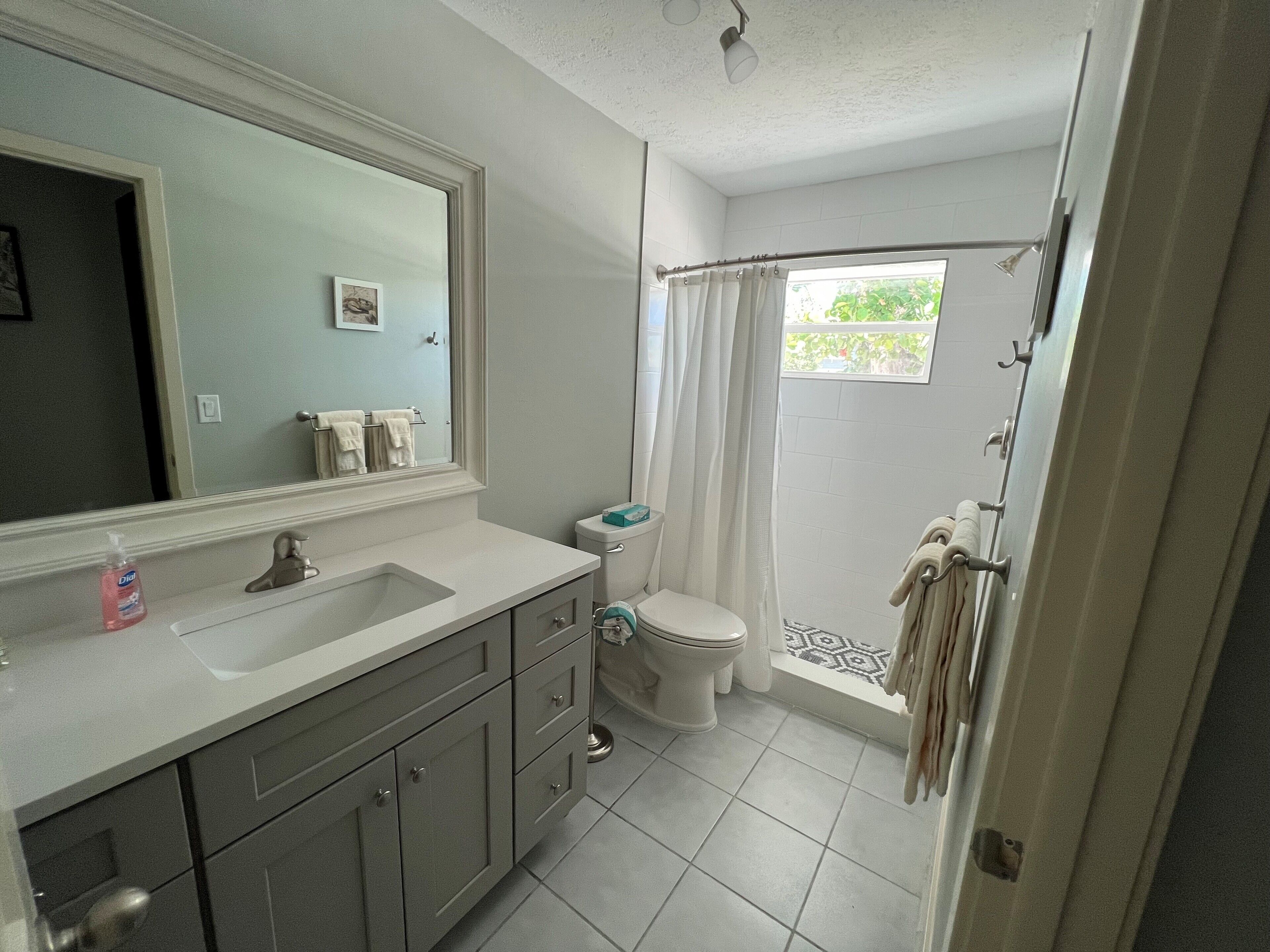 Baño con lavamanos, inodoro y cortina de ducha.