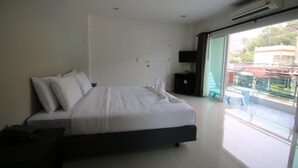 Habitación de hotel moderna con una cama grande, un televisor de pantalla plana y un ventanal corredero que da a un balcón.