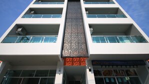 A multi-story building with a central vertical feature, large windows, and a storefront with food images. - Karon Sea Side (Karon)