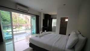 A hotel room with a large bed, a sliding glass door leading to an outdoor area, and a separate bathroom. - Karon Sea Side (Karon)