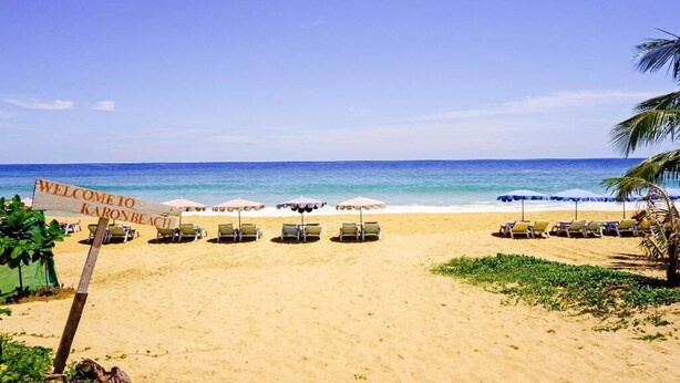 A beach with a 'Welcome to Karon Beach' sign, sun loungers, and umbrellas. - Karon Sea Side (Karon)