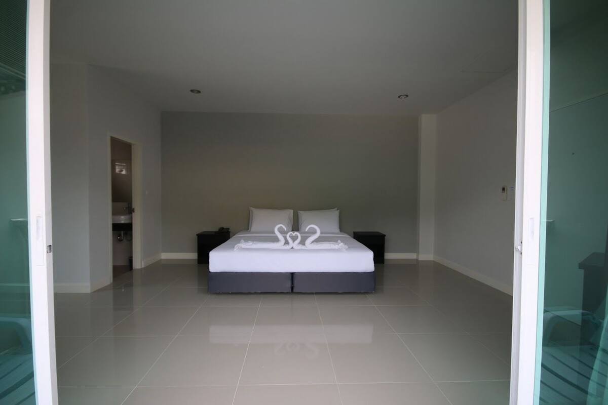 Un dormitorio moderno con una cama grande, dos mesitas de noche y una puerta de vidrio que da a otra habitación.