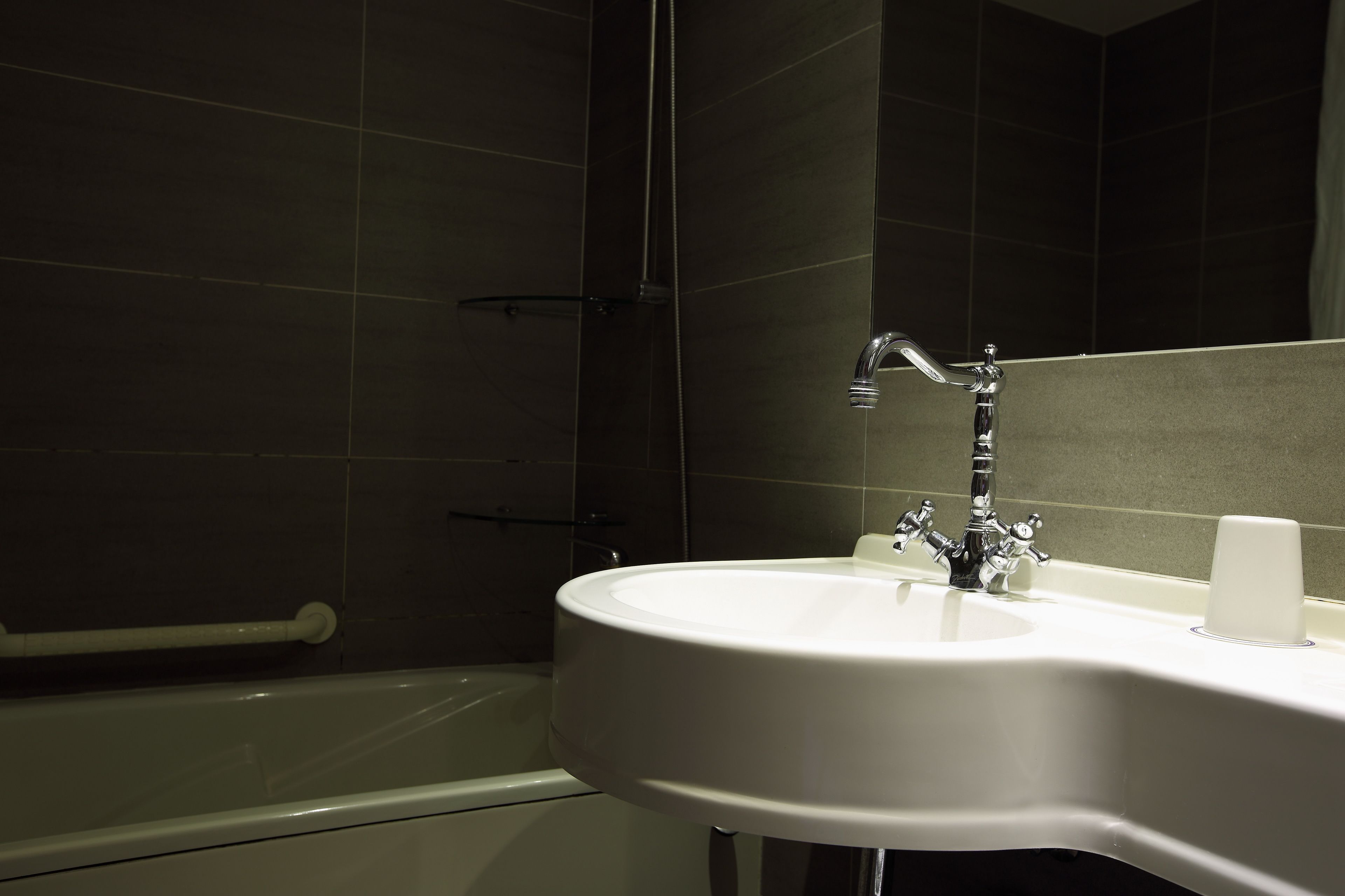 A bathroom with a white sink, a mirror, and a shower area.