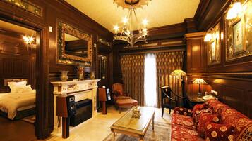 A luxurious room with a large bed, a fireplace, a red sofa, and a chandelier.