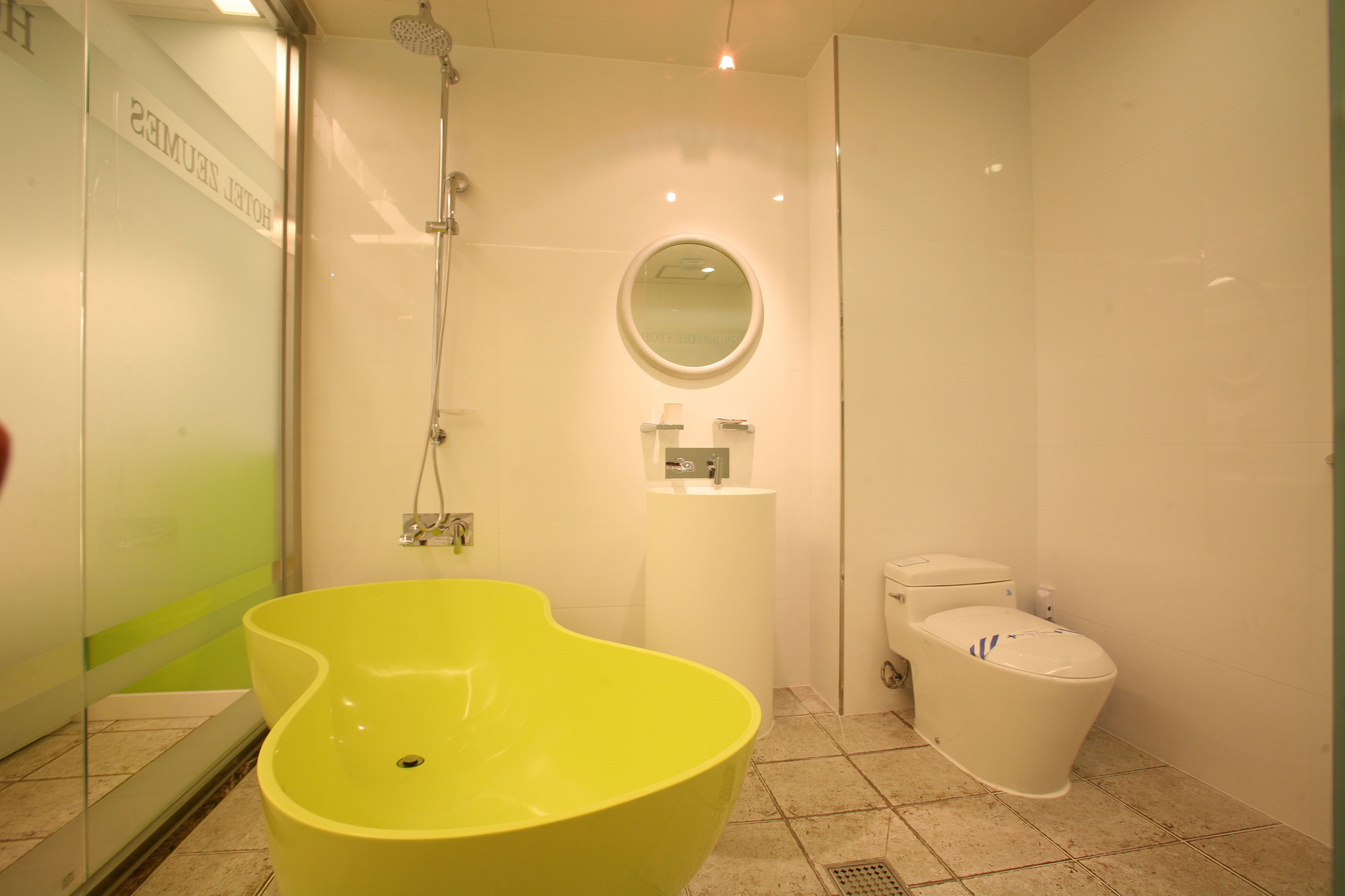 Ein modernes Badezimmer mit einem großen, gelben Waschbecken, einer Toilette und einer Dusche.