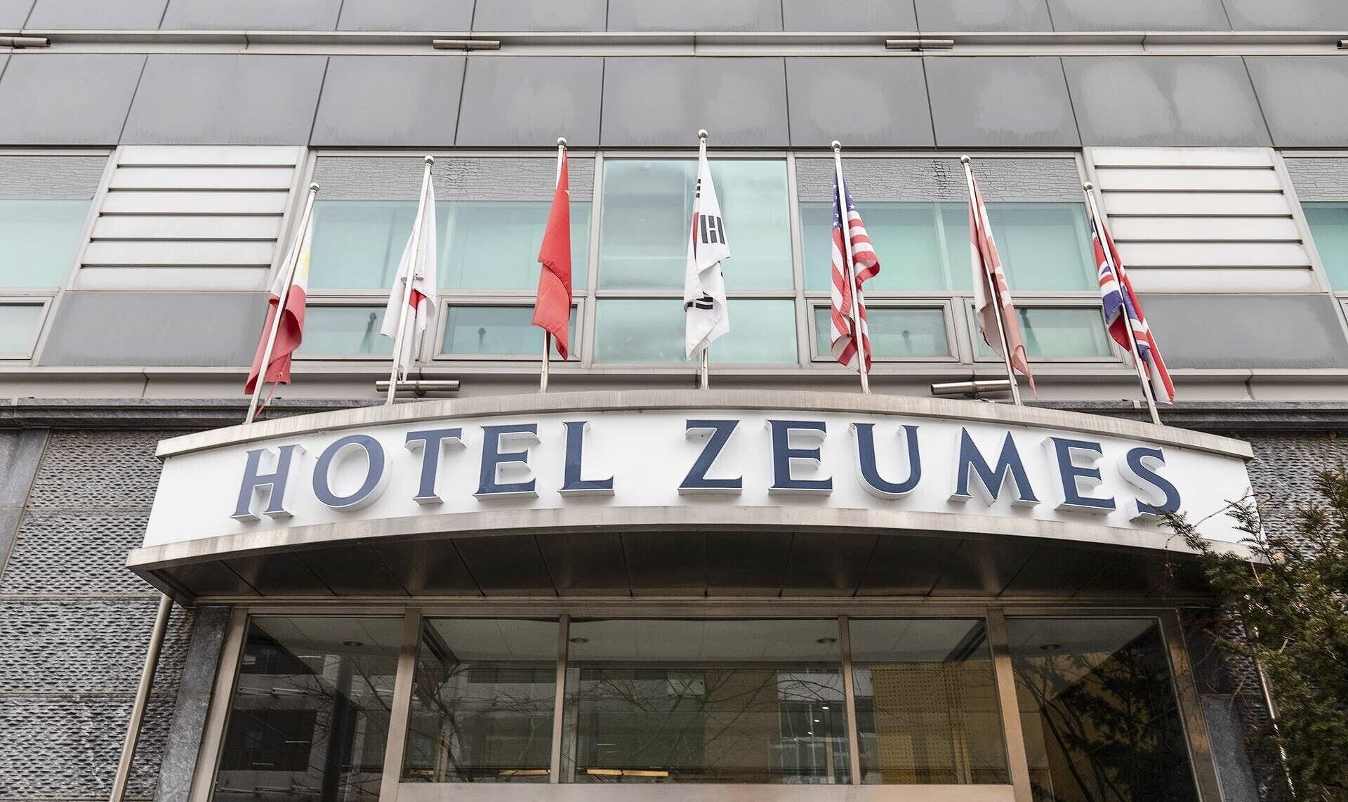 Hotel Zeumes' facade med tydelig skilt og flere flag.