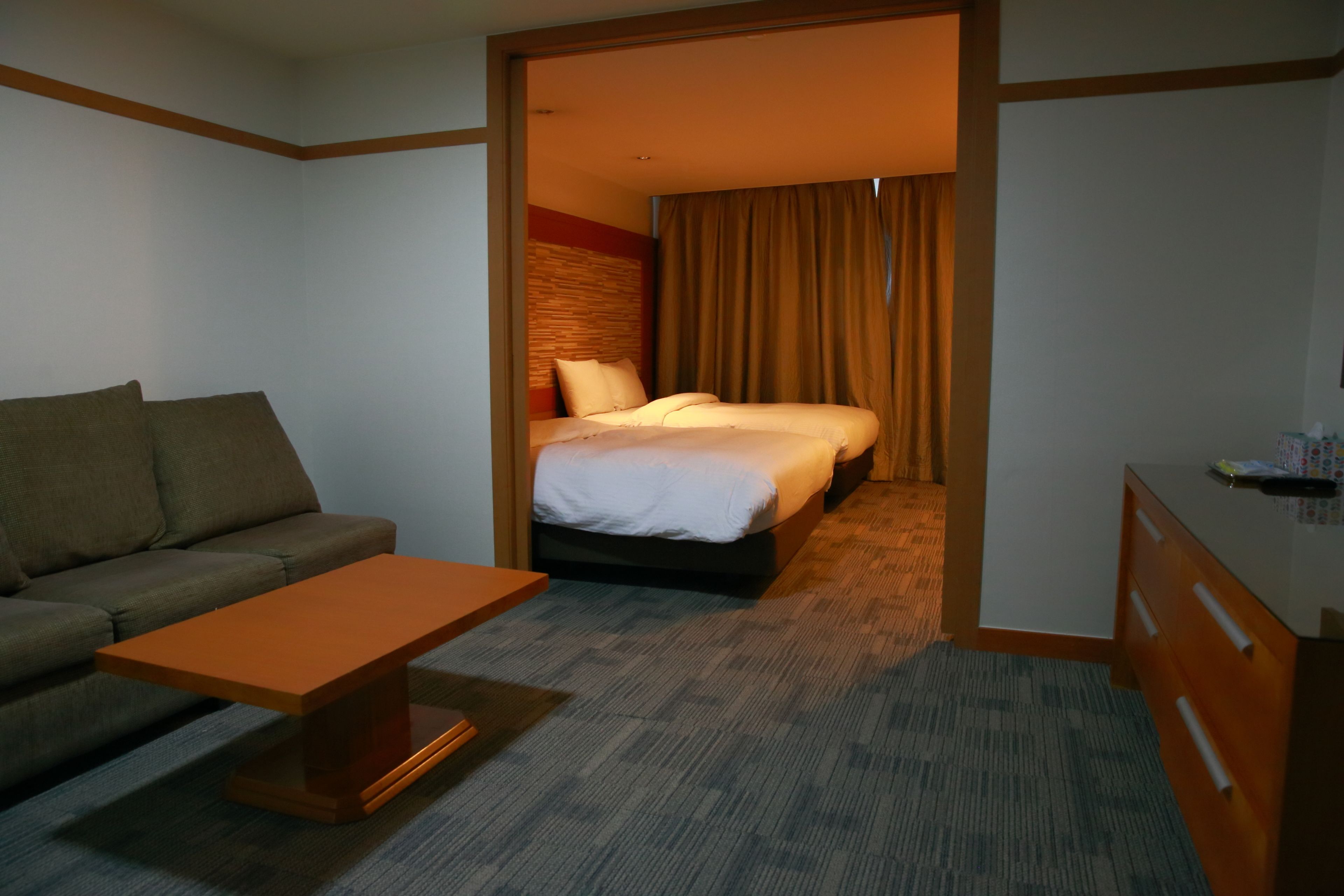 A hotel room with a bed, a sofa, a desk, and a carpeted floor.