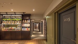 A hotel corridor with a display of plush toys and souvenirs, a carpeted floor, and a door marked with the number 205. - Urtrip Hotel (Taipei)