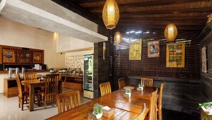 A restaurant with wooden tables and chairs, hanging lights, and various signs on the walls. - Kadiga Villas Ubud by GenuineHost (Ubud)