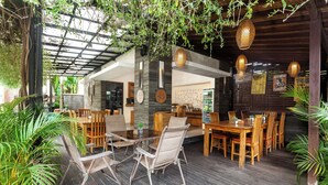 An outdoor dining area with wooden tables and chairs, surrounded by potted plants and hanging lanterns. - Kadiga Villas Ubud by GenuineHost (Ubud)