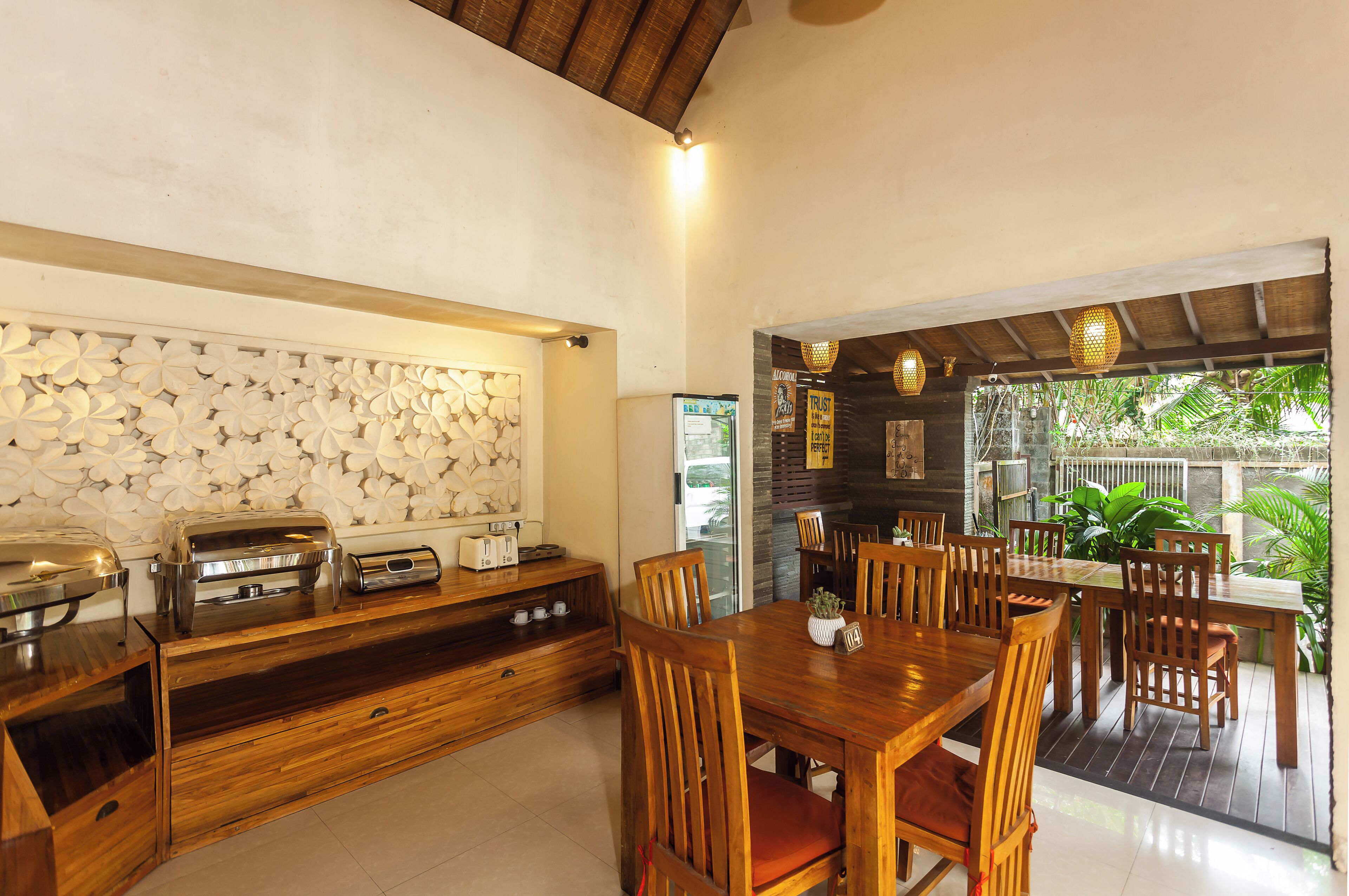 A wooden dining area with a large table and chairs, a buffet counter with food items, and a decorative wall with a floral pattern.