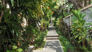 A narrow pathway flanked by lush greenery and a stone wall, leading to a building entrance. - Kadiga Villas Ubud by GenuineHost (Ubud)