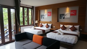 Habitación de hotel con dos camas, un sofá y un balcón con vistas a zonas verdes.