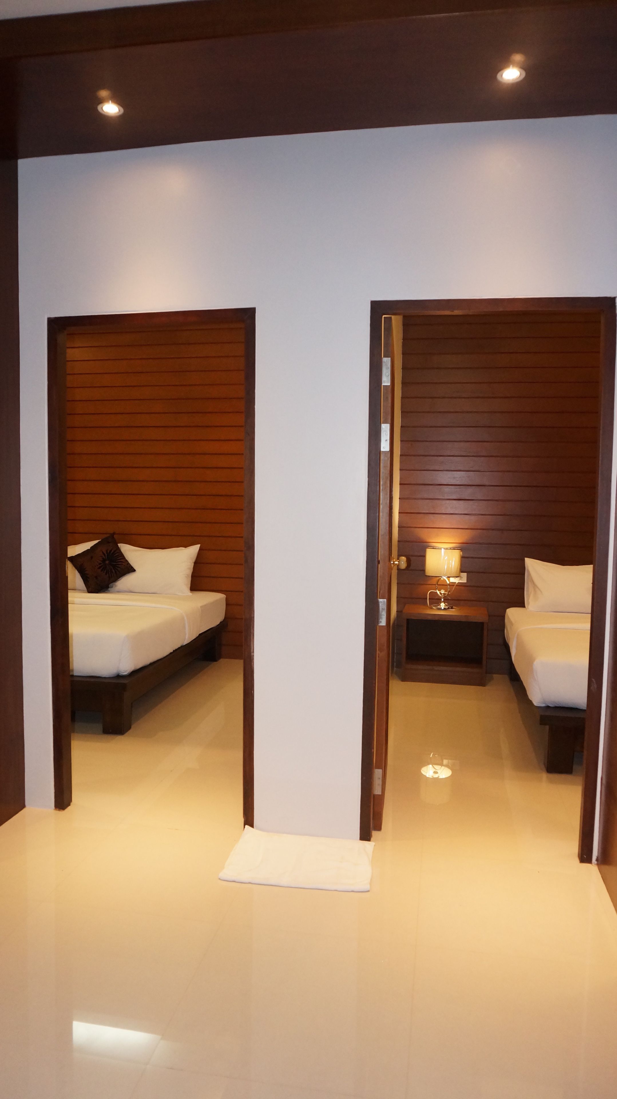 Una habitación de hotel con dos camas, una mesita de noche con lámpara y un panel de pared de madera.