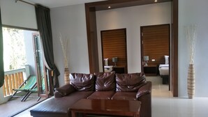 Una sala de estar moderna con un sofá de cuero, una mesa de centro de madera y un ventanal que da a un balcón.