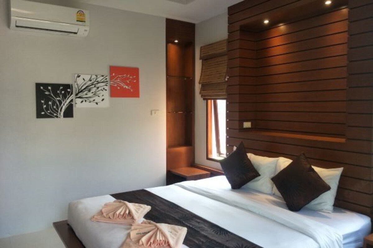 A modern hotel room with a bed, artwork on the wall, and a window with blinds.