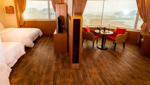 Una habitación de hotel con una cama, una pequeña mesa con sillas y un ventanal con vistas al mar.