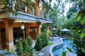 Un hôtel doté d’une piscine, d’un espace extérieur aménagé et d’une végétation luxuriante.