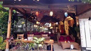 An indoor restaurant with wooden furniture, hanging lights, and greenery. - Rahayu 2 Bungalows (Ubud)