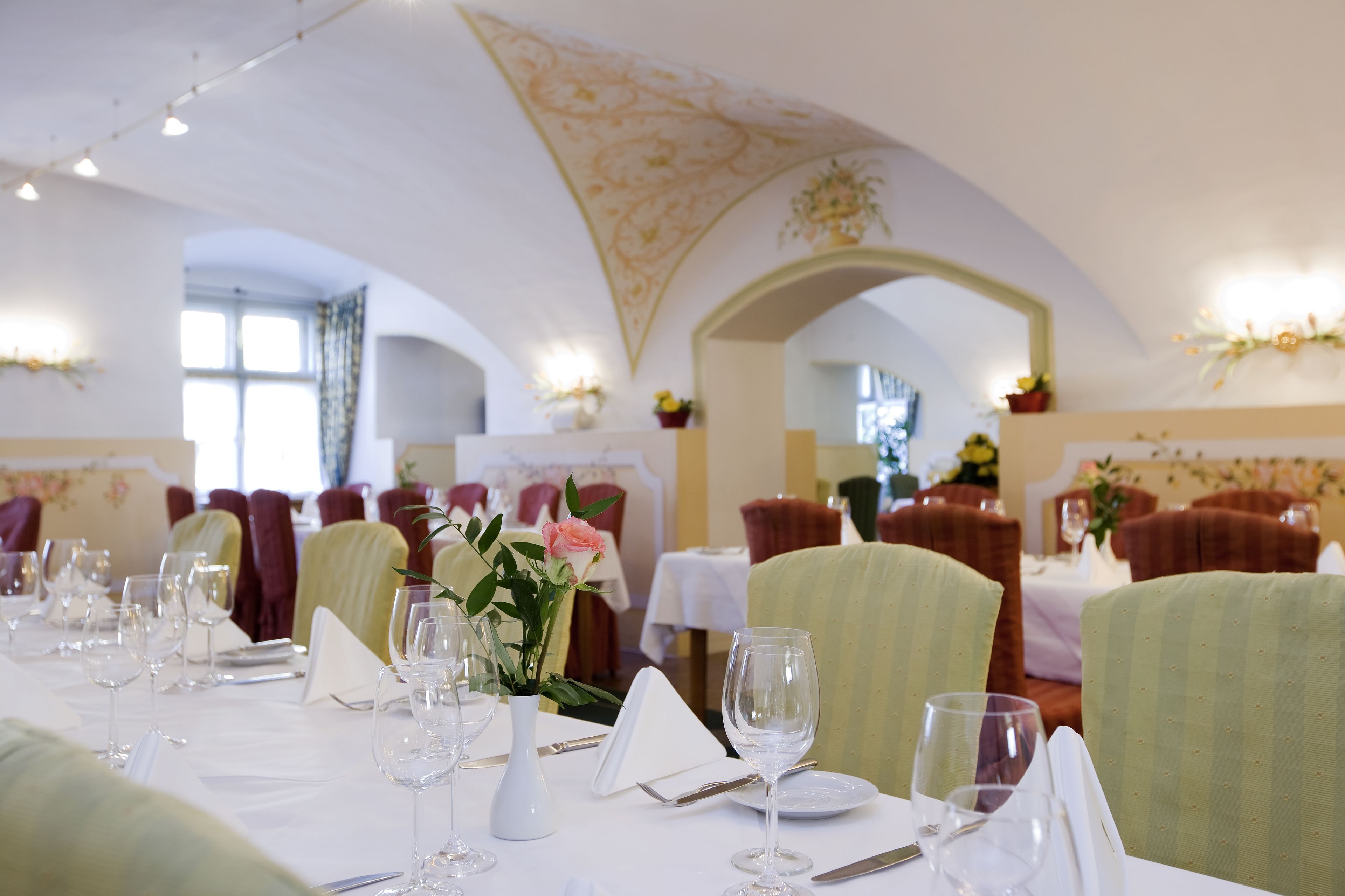 Comedor con mesas dispuestas para una comida, sillas y un techo decorativo.