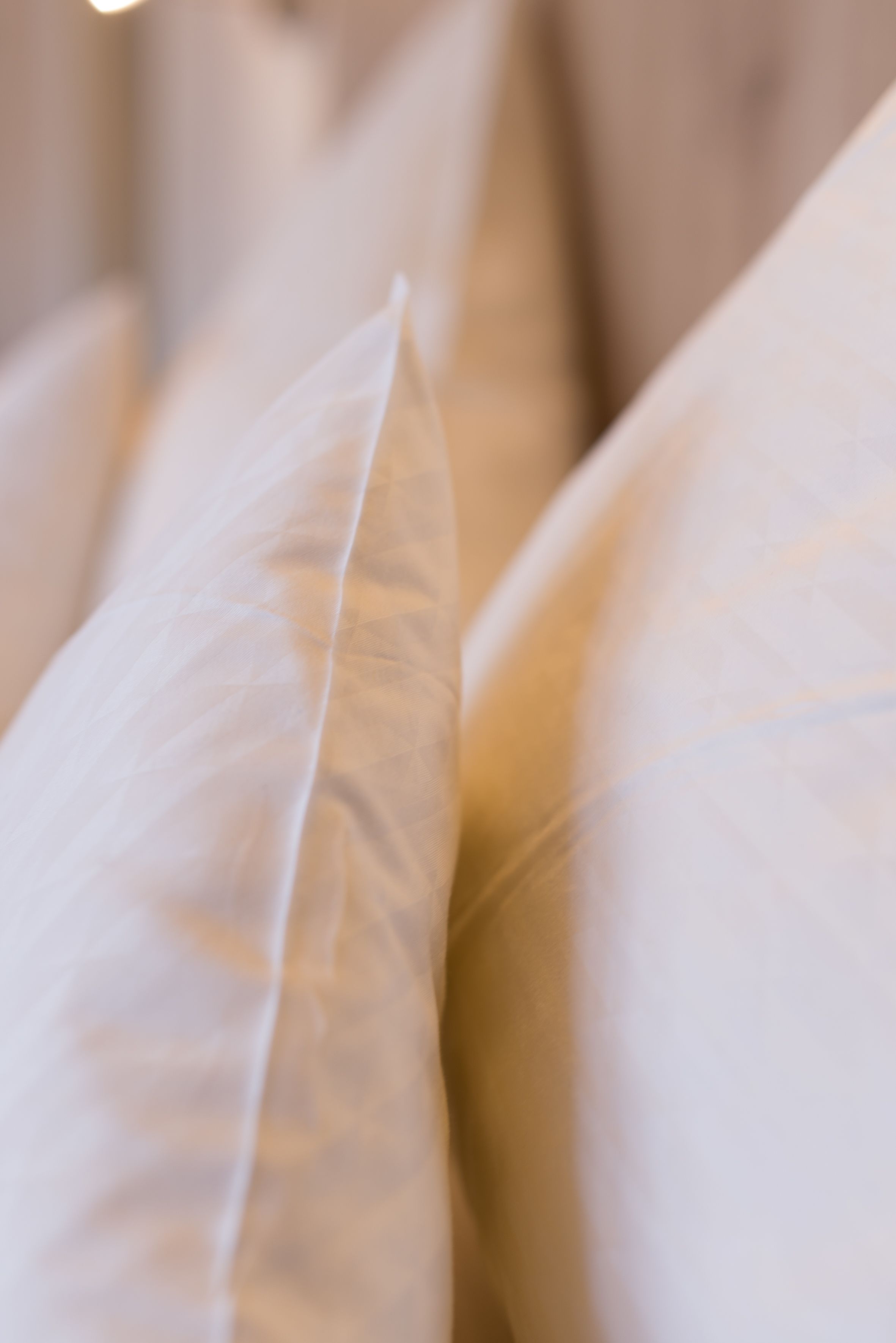 A close-up of a bed with white linens.