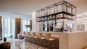 Un espace bar moderne doté d’un îlot central, de tabourets de bar et d’un meuble à vin.