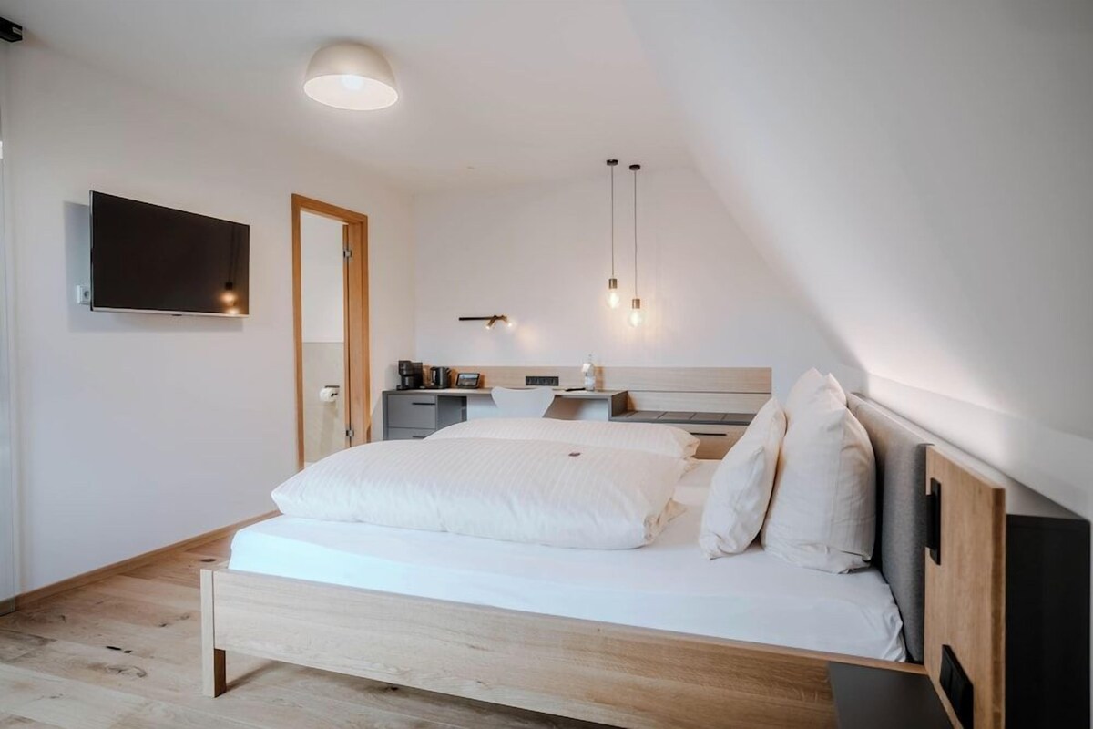 A bedroom with a bed, bedside tables, a TV, and a desk with a chair.