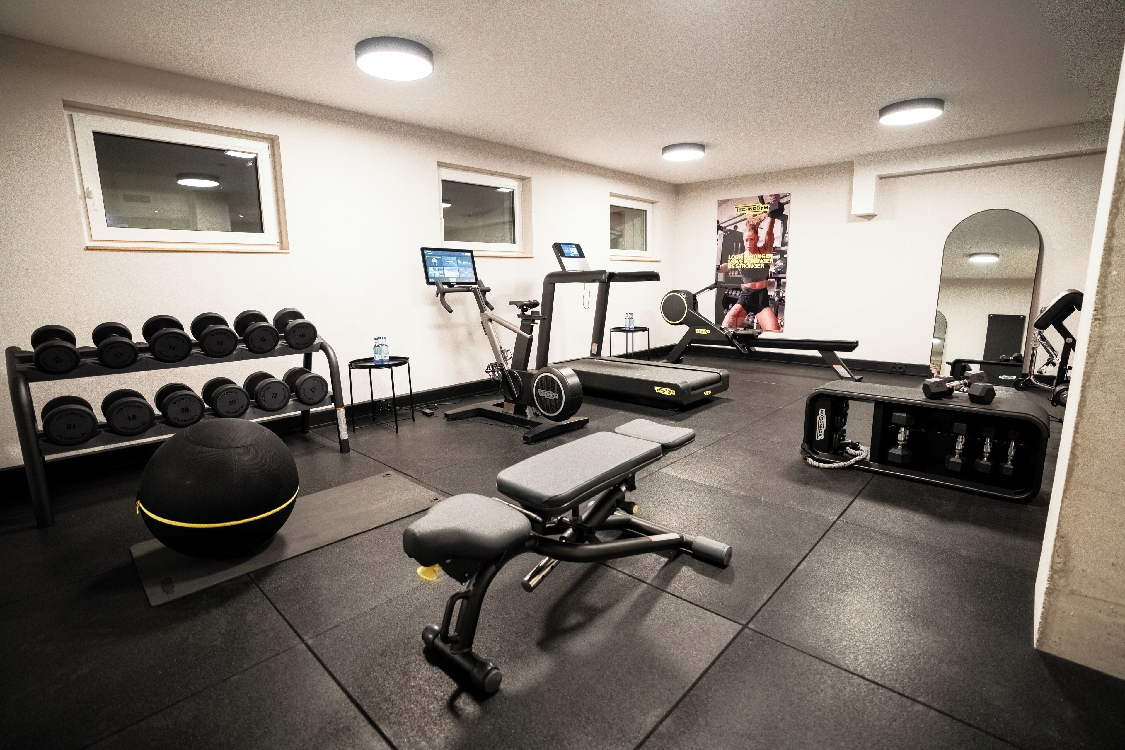 Une salle de sport équipée de machines d’exercice, d’haltères et d’un banc.