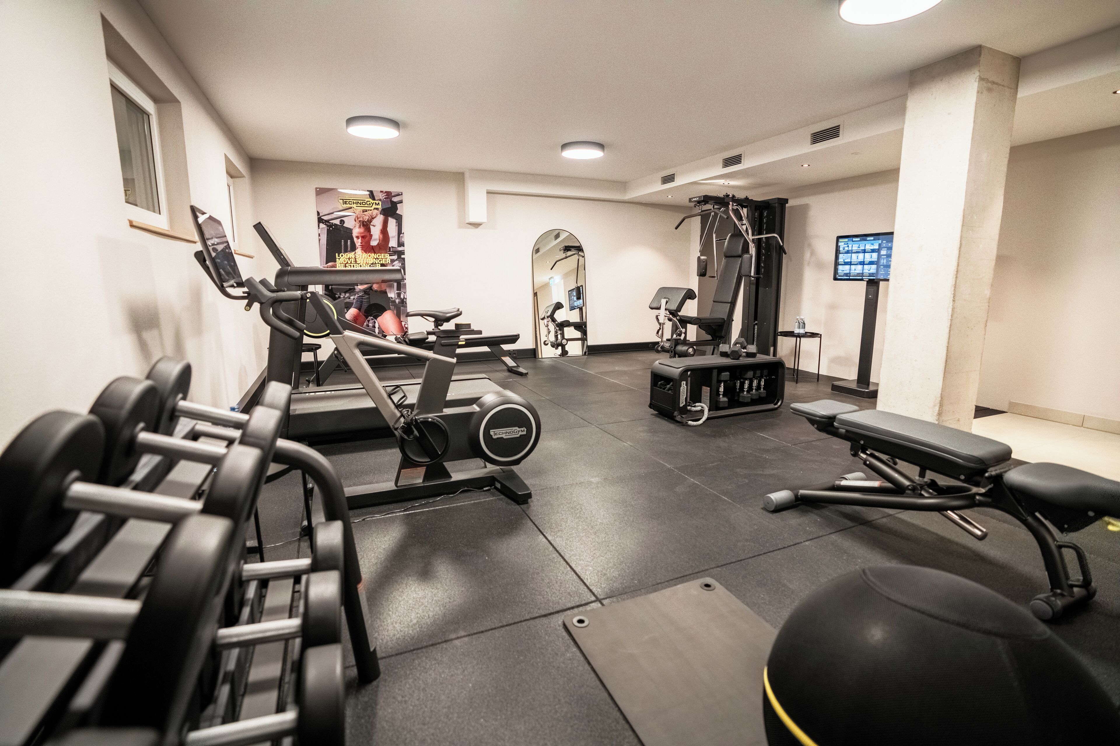A gym with various exercise equipment, including treadmills, weight machines, and free weights.