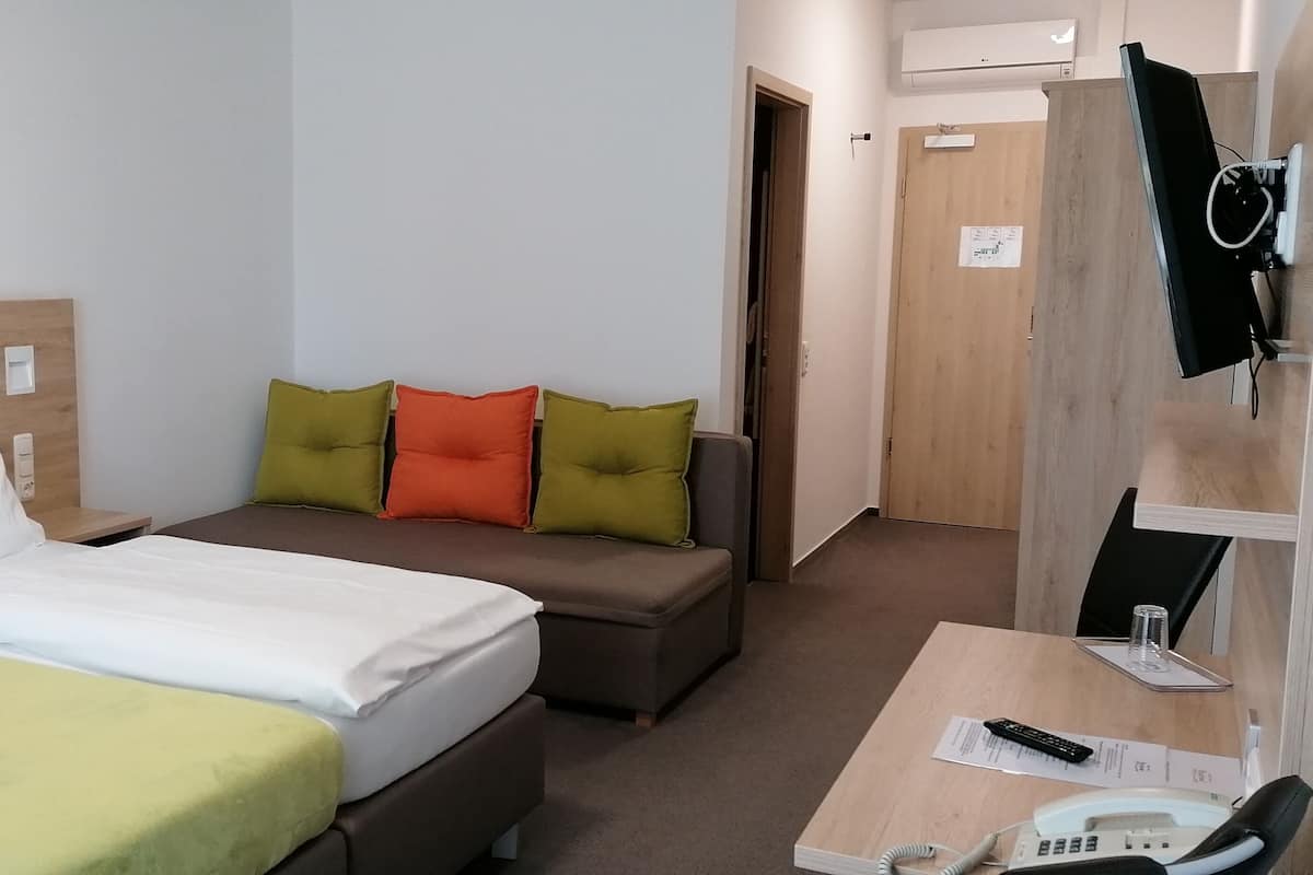 Ein Hotelzimmer mit zwei Betten, einem Schreibtisch mit Telefon und Fernbedienung sowie einer Tür zu einem Badezimmer.