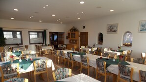 A dining area with multiple tables and chairs, each with a green tablecloth and patterned chair upholstery. - Gasthaus Pension Rezatgrund (Windsbach)