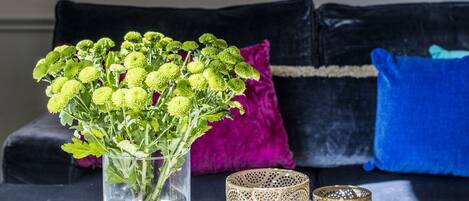 Een tafel met een vaas groene bloemen, twee sierlijke kandelaars en een kleine schaal.