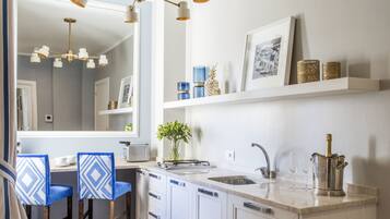 A modern kitchen with white cabinetry, a central island with a sink, and a dining area with blue chairs.