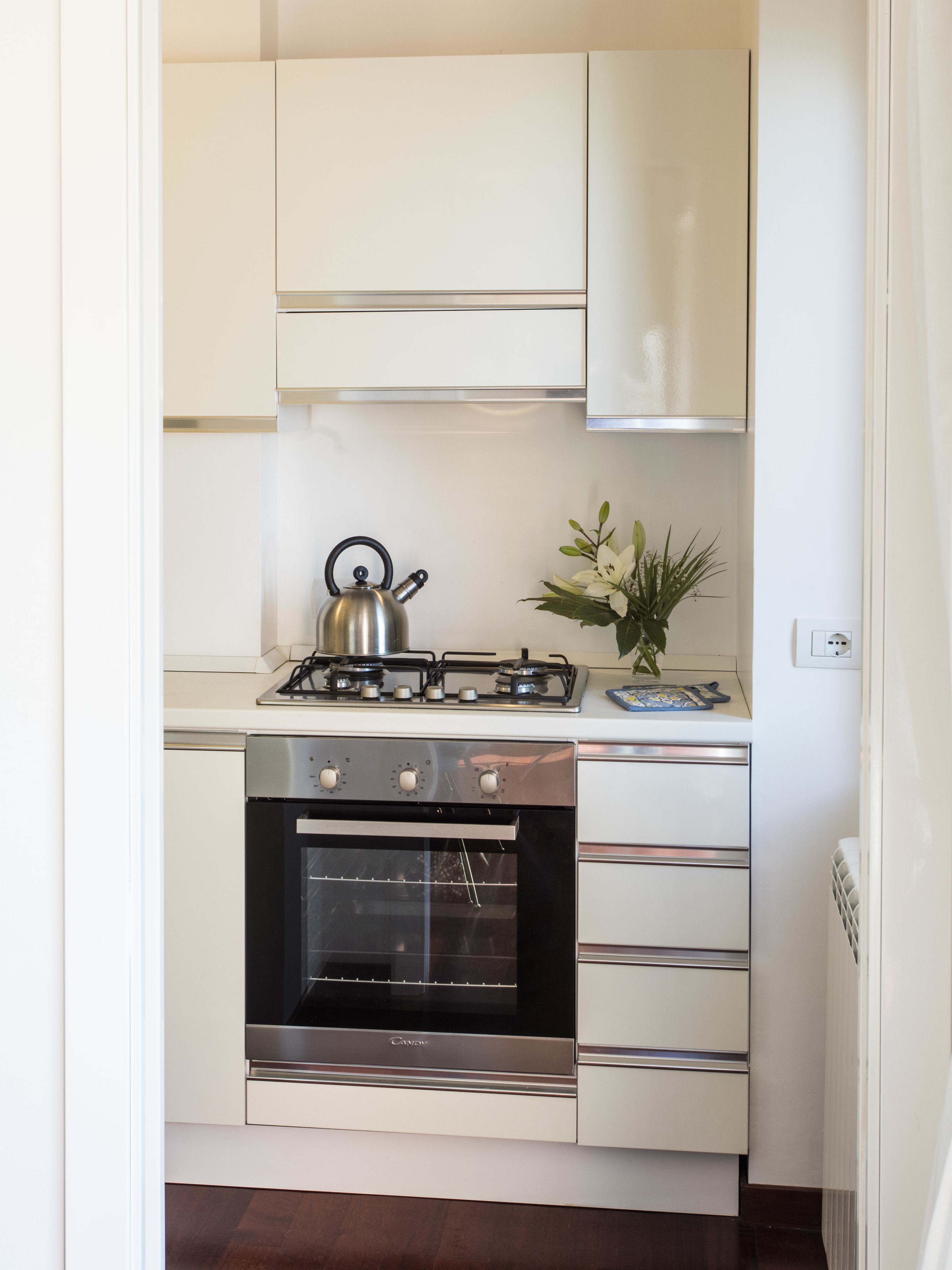 A compact kitchen with a gas stove, oven, and white cabinetry.