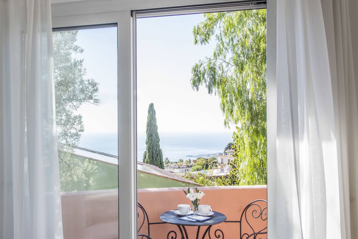 Une pièce dotée d’une porte-fenêtre coulissante donnant sur un balcon extérieur avec une table et des chaises.