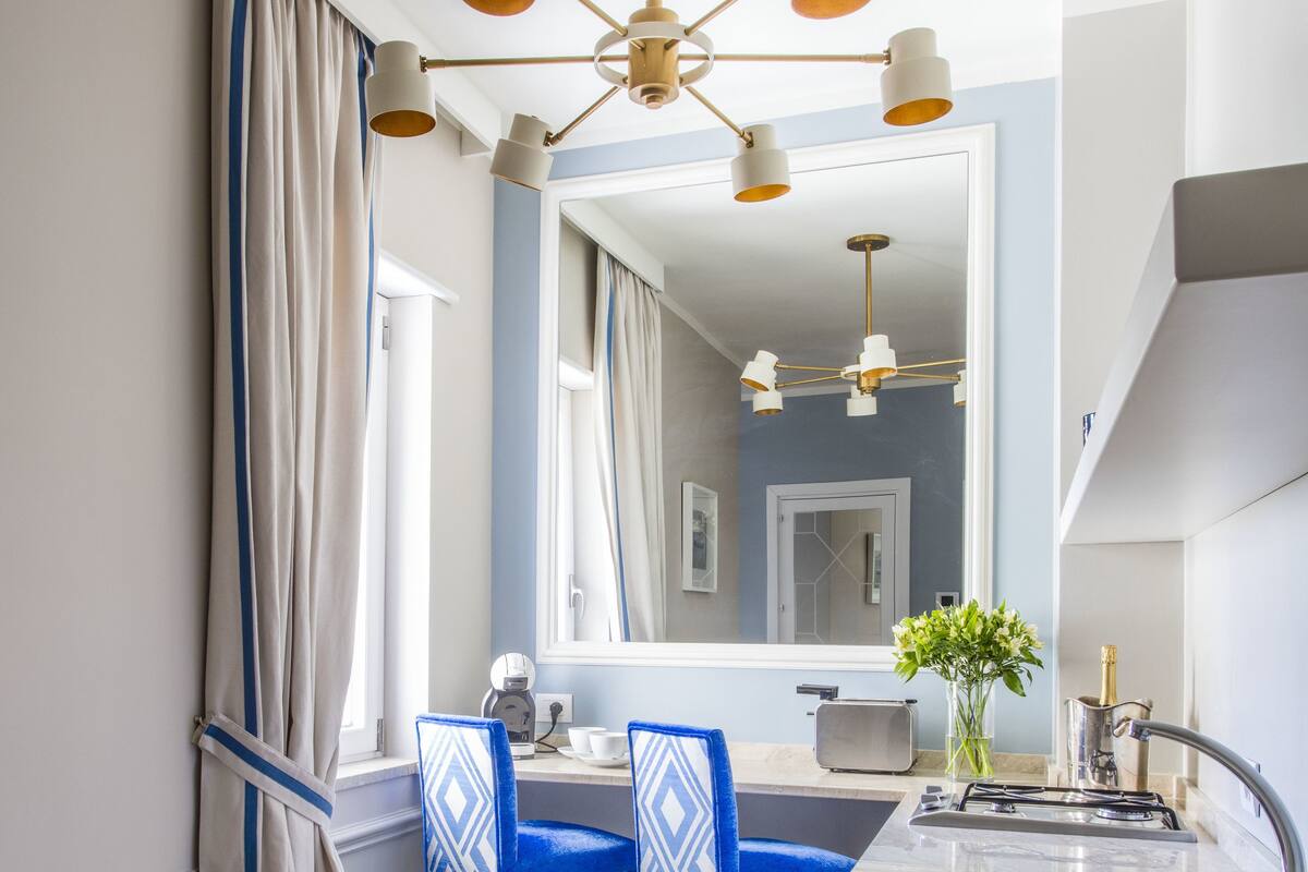 Une cuisine moderne dotée d’un plan de travail en marbre, d’un évier et d’un coin repas avec des chaises bleues.
