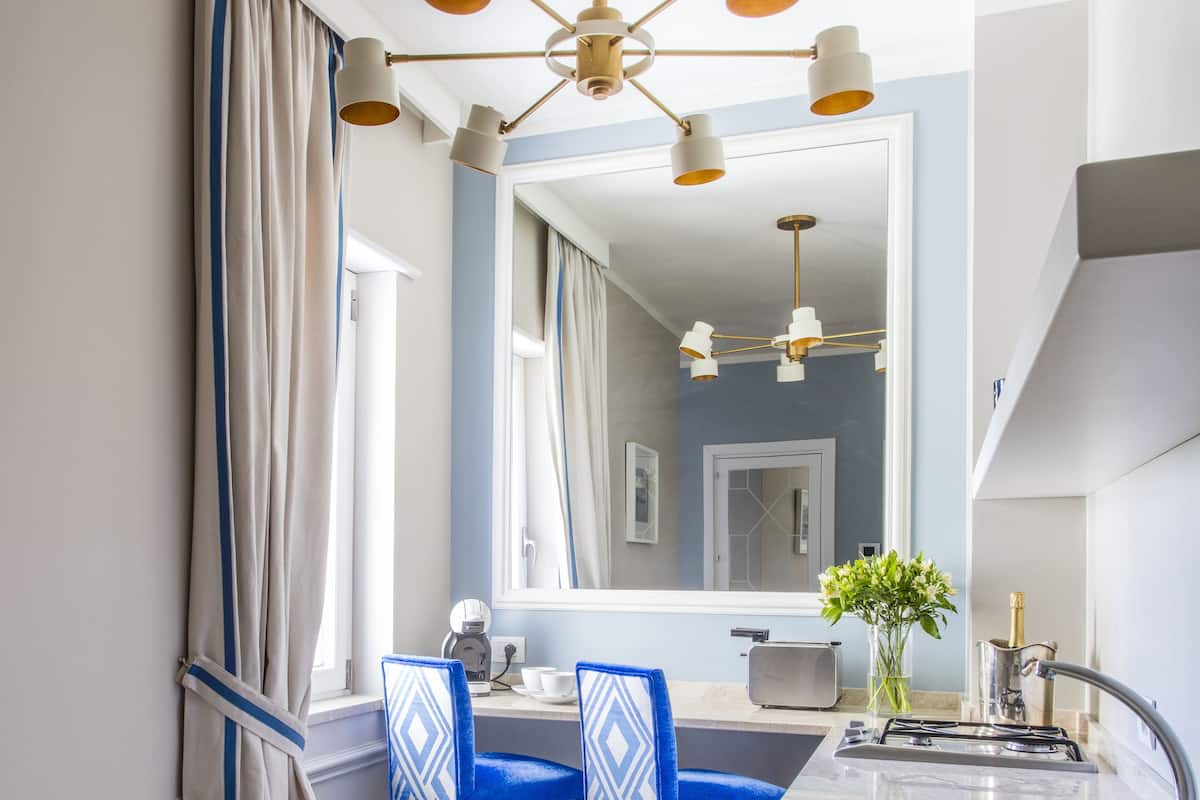 A modern kitchen with a marble countertop, a sink, and a dining area with blue chairs.