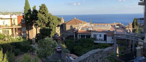 A coastal town with stone buildings, a stone bridge, and a view of the sea.