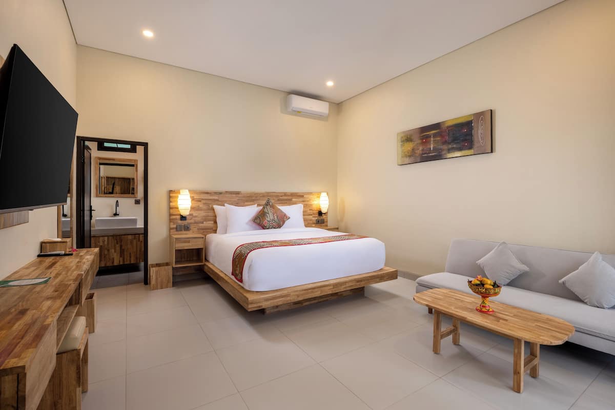 A modern hotel room with a wooden bed, a sofa, a wooden desk, and a TV.