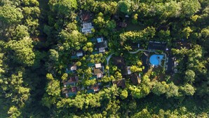 An aerial view of a residential area with multiple houses surrounded by dense greenery, a swimming pool, and a small road. - Senetan Villas and Spa Resort (Payangan)