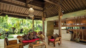 A spacious lobby with wooden furniture, a reception desk, and a view of lush greenery outside. - Senetan Villas and Spa Resort (Payangan)